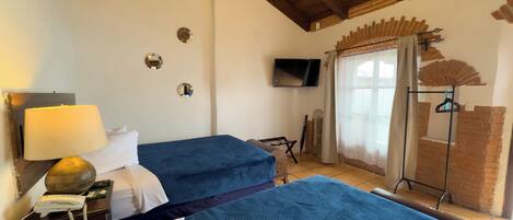 A room with two beds, a TV, a lamp, and a brick wall.