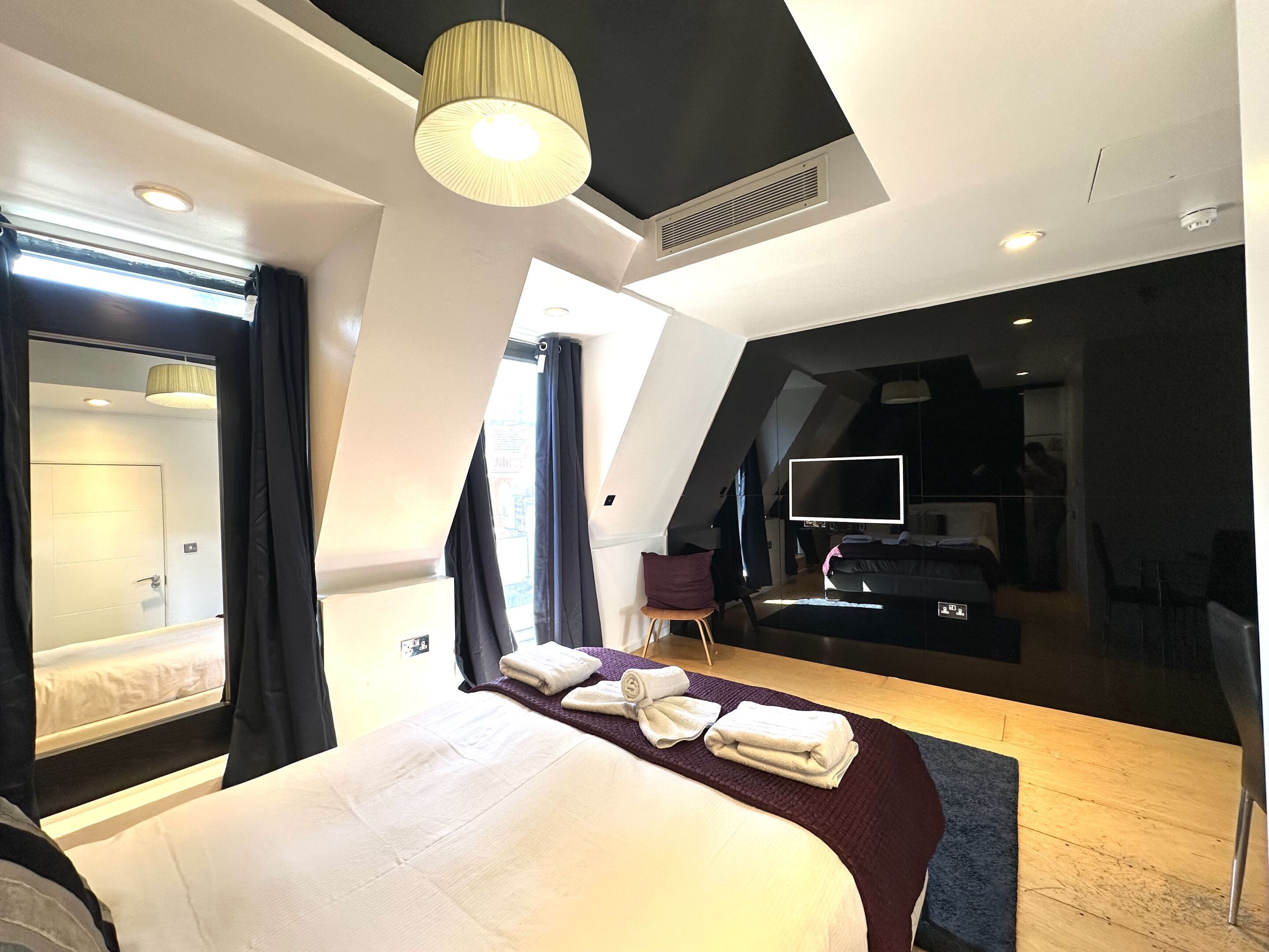 Ein modernes Hotelzimmer mit einem großen Bett, einem Flachbildfernseher und Blick auf die Stadt durch das Fenster.