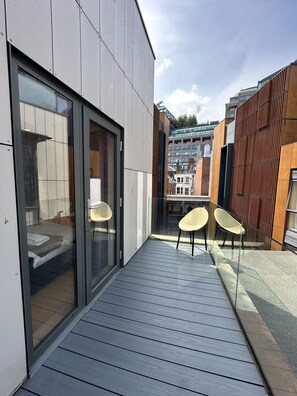 A modern building with a balcony, two chairs, and a glass door leading to a room. - Room Home Stay (London)