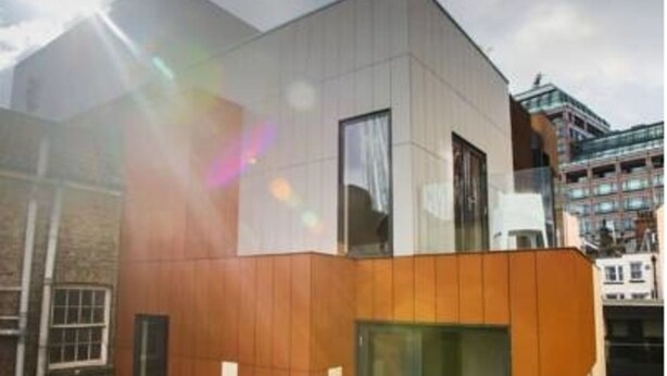 A modern building with a flat roof, large windows, and a mix of brick and wood paneling. - Room Home Stay (London)