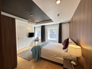 Une chambre à coucher avec un lit, une lampe de chevet et un téléviseur fixé au mur.