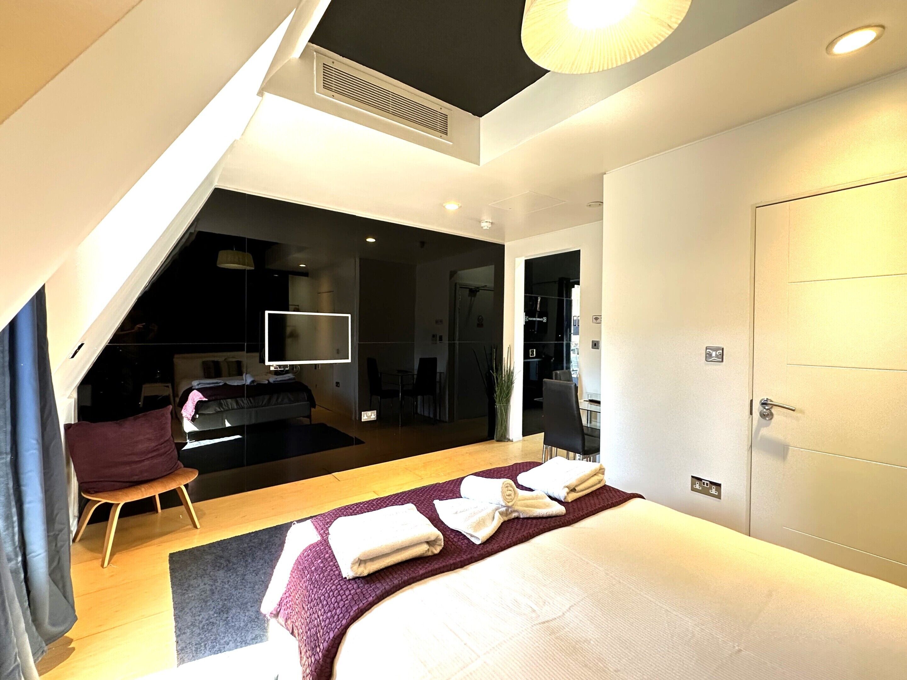 Quarto de hotel moderno com cama, escrivaninha e televisão.
