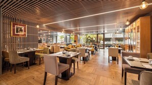 Un restaurant moderne avec des plafonds à lattes de bois, un plancher en bois et un mélange de chaises tapissées de jaune et de gris.