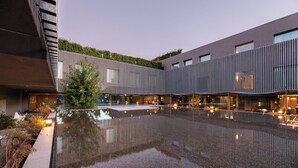 Un bâtiment moderne doté d’un bassin d’eau réfléchissant, d’espaces aménagés pour s’asseoir et d’un jardin bien entretenu.