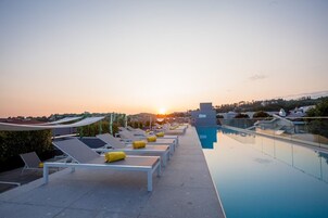 Zona de piscina en la azotea con tumbonas y una vista despejada del atardecer.