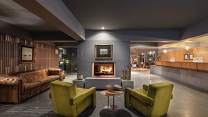 Un espace de détente moderne avec une cheminée, un canapé en cuir et des fauteuils verts.
