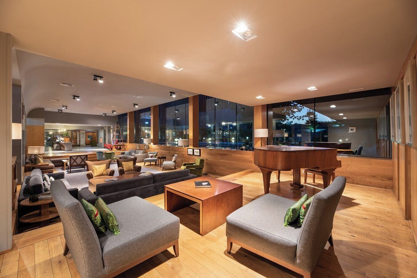 A spacious lobby with a grand piano, comfortable seating, and large windows offering city views.