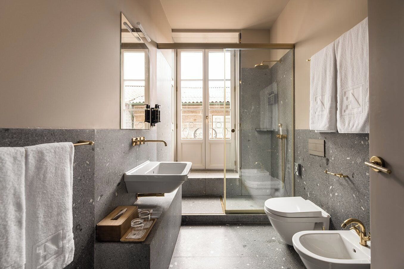 A modern bathroom with a large mirror, two sinks, a toilet, and a shower area.