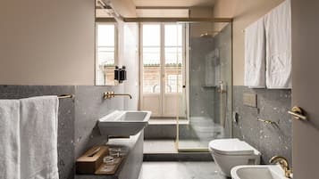 A modern bathroom with a large mirror, two sinks, a toilet, and a shower area.