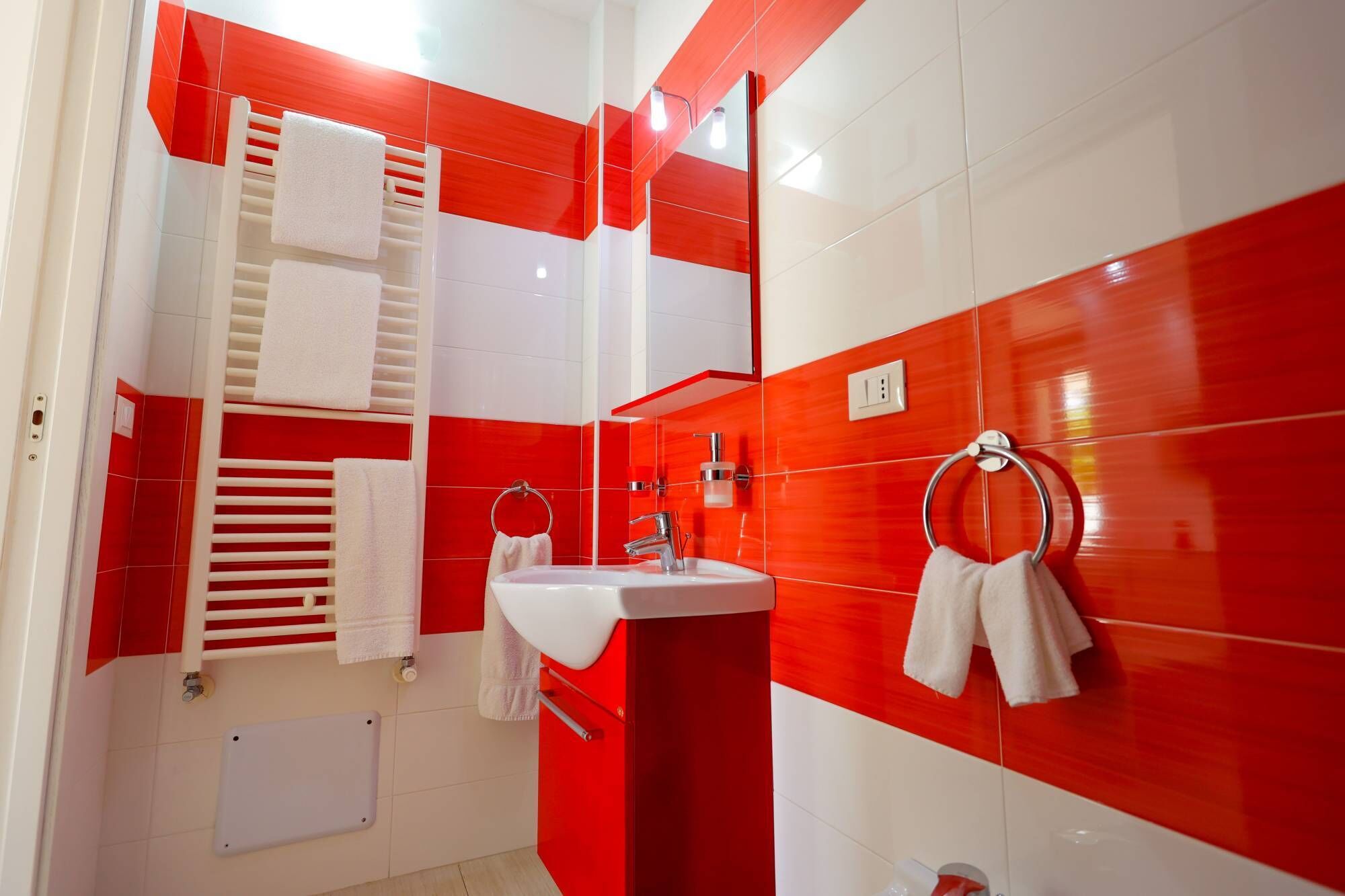 Un baño moderno con un lavamanos blanco, un espejo y un perchero para toallas.