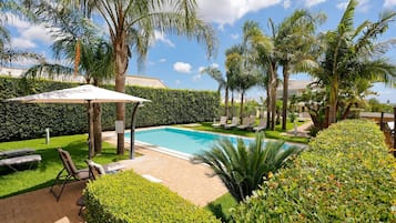 Una piscina al aire libre, sillones reclinables de piscina