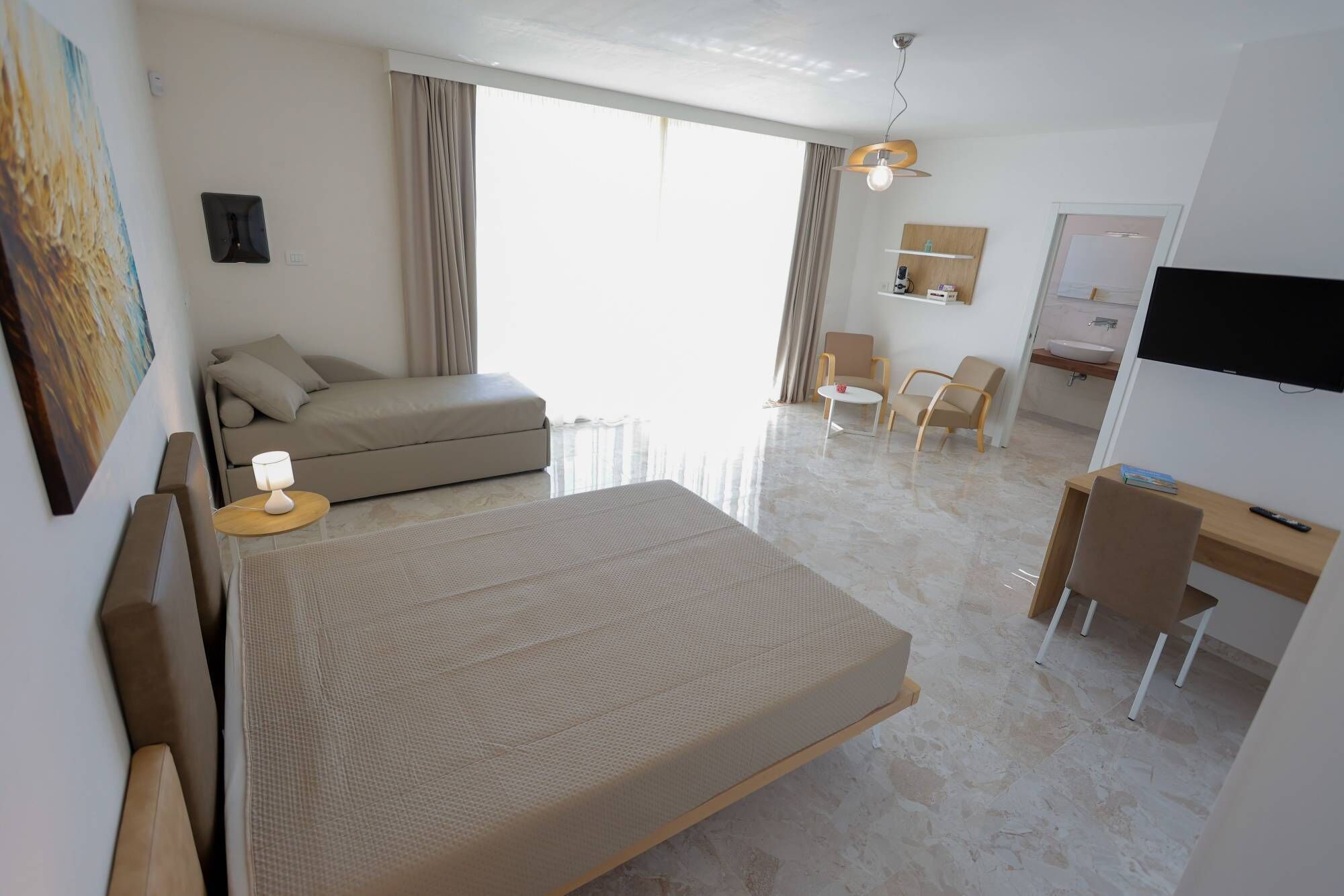 Une chambre d’hôtel comprenant un lit, un bureau, une chaise, une télévision et une salle de bain.