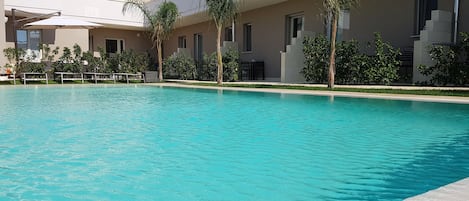 Una piscina al aire libre, sillones reclinables de piscina