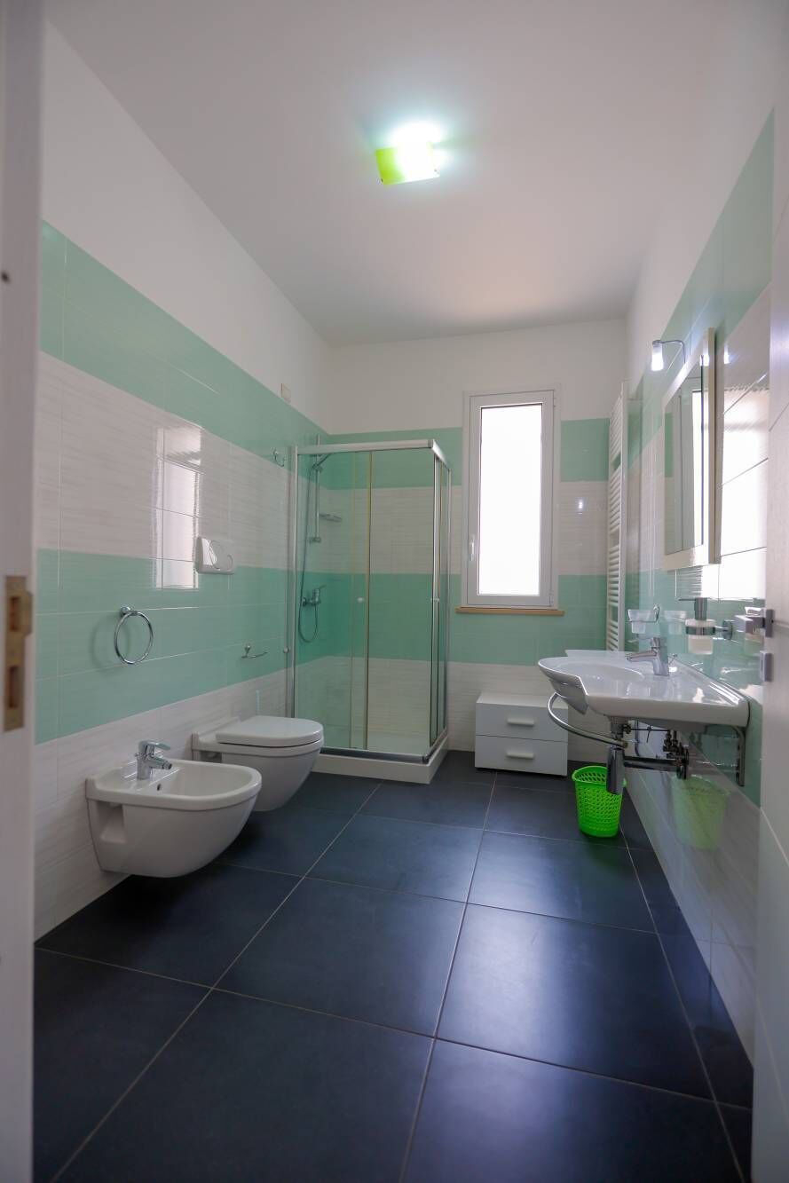 A bathroom with a shower, toilet, bidet, and sink.
