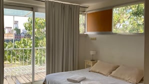 A bedroom with a bed, a window, a nightstand, and a view of greenery outside.