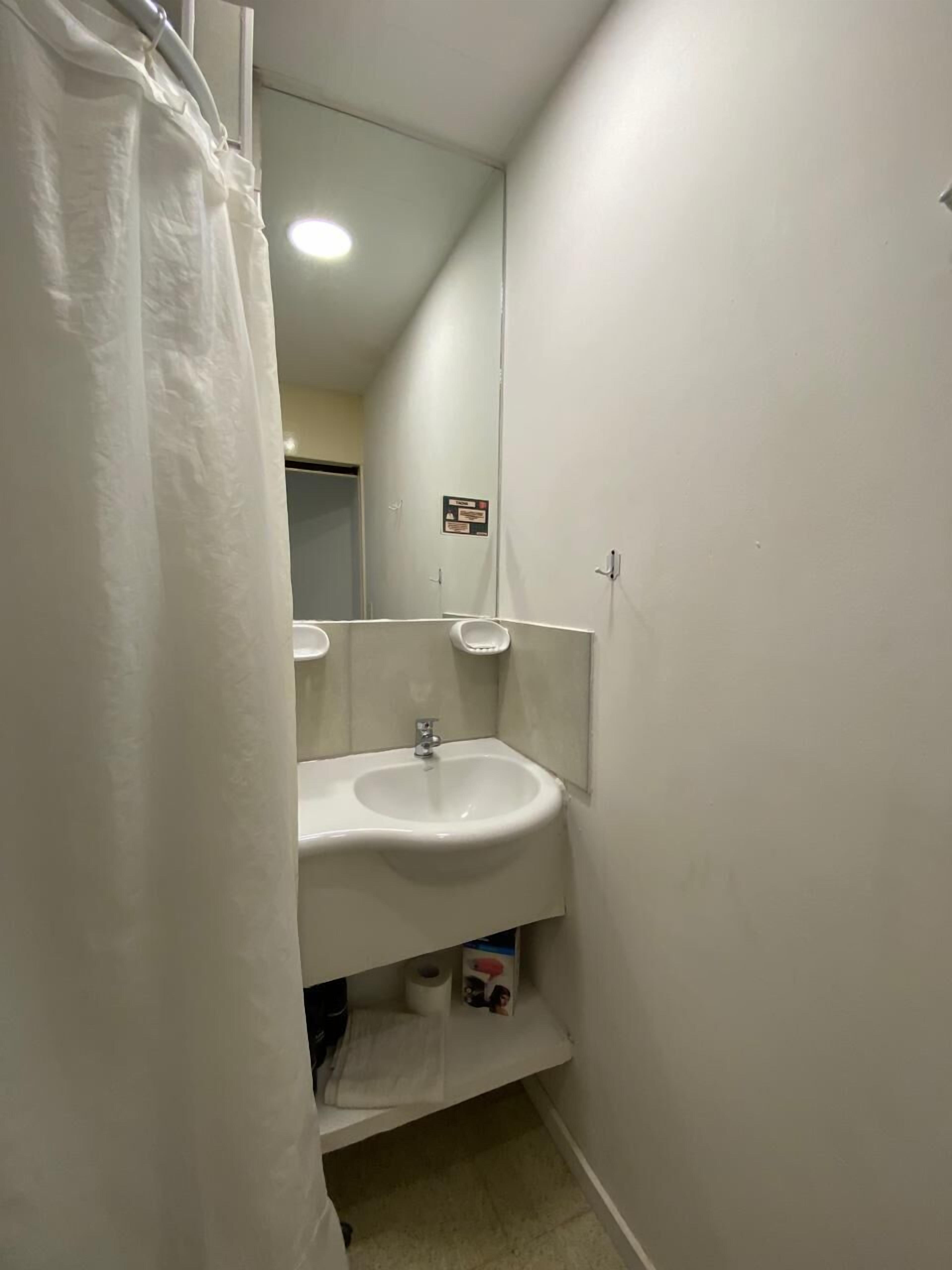 A bathroom with a white sink, a mirror, and a shower curtain.