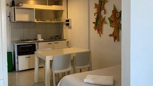 A compact hotel room with a kitchenette, a dining area, and a bed.