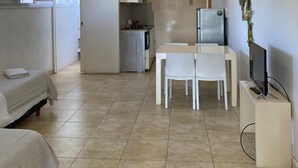 A modern living room with a dining area, a kitchen, and a bedroom.
