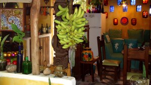 A cozy room with a wooden ceiling, a refrigerator, a chair, and a table with various items. - Casitas Kinsol (Puerto Morelos)