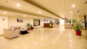 A spacious lobby with a reception desk, seating area, and potted plants.
