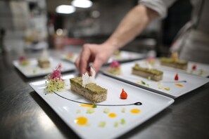 Een kok legt een dessert op een wit bord met artistieke garneringen.