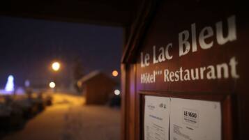 A sign for "Le Lac Bleu Hotel Restaurant" with a menu board visible.
