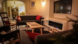Un salon chaleureux avec une cheminée, un canapé, une table basse et un téléviseur fixé au mur.