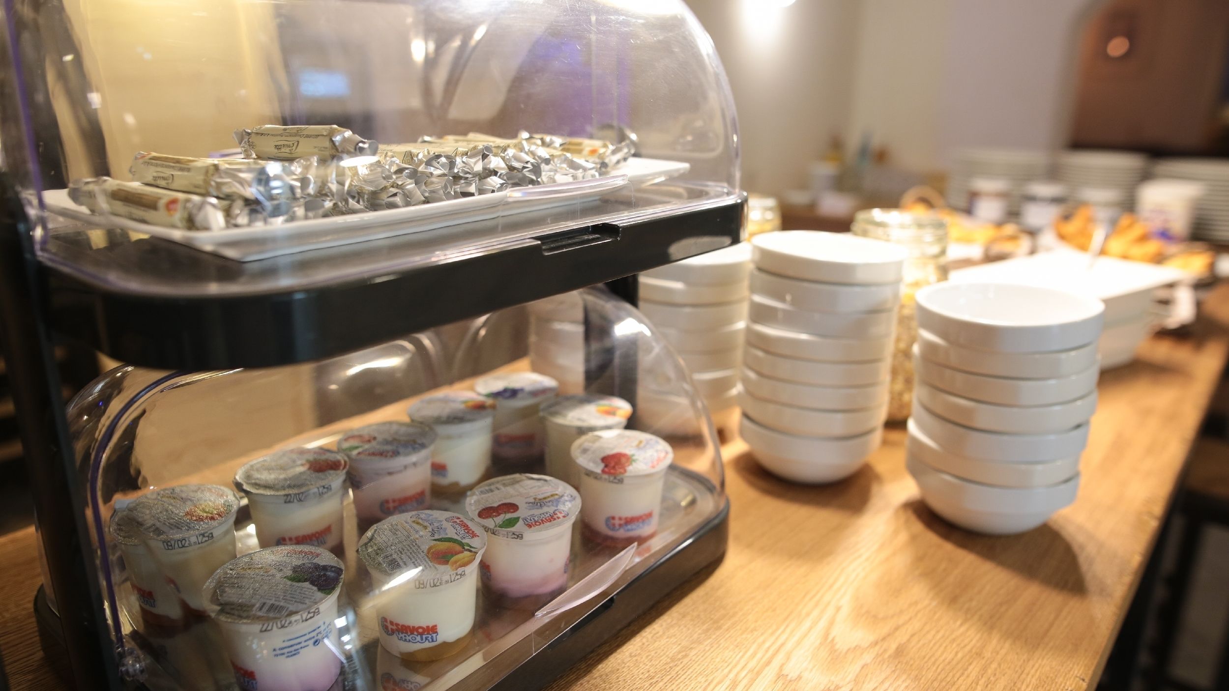 A buffet with various food items, including yogurt cups and a tray of wrapped items.