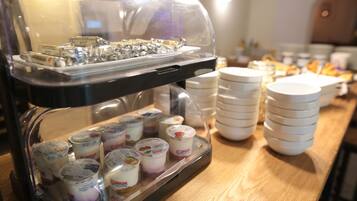 A buffet with various food items, including yogurt cups and a tray of wrapped items.