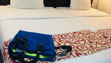 A hotel room with a large bed, white bedding, a headboard, and a wall-mounted picture.