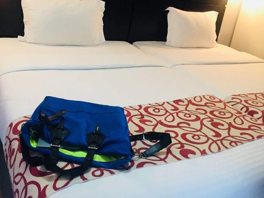 A hotel room with a large bed, white bedding, a headboard, and a wall-mounted picture.