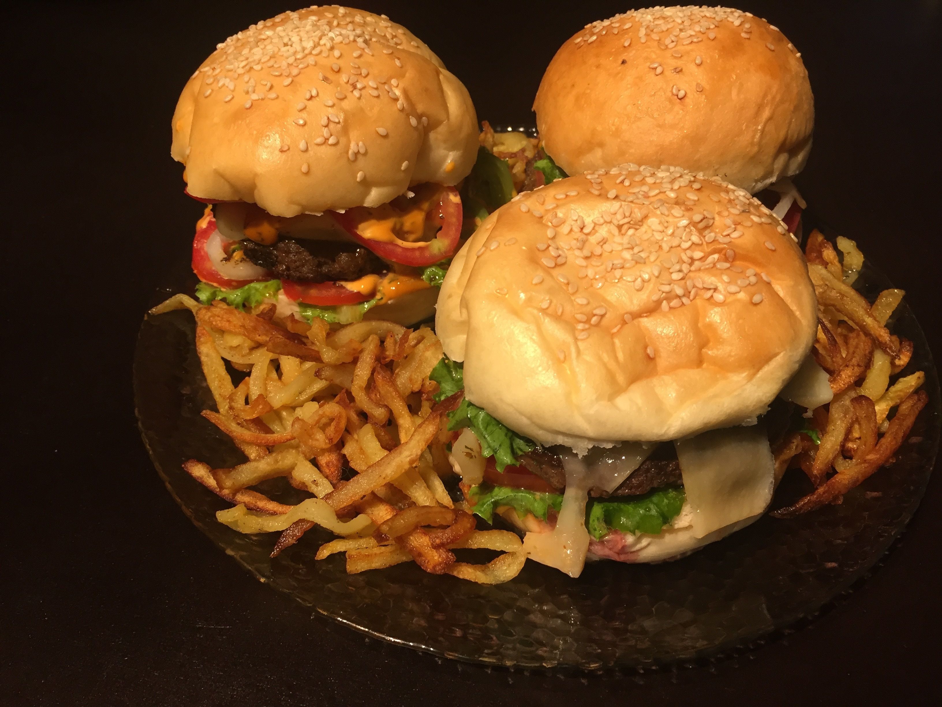 Ein Teller mit drei Burgern und Pommes.