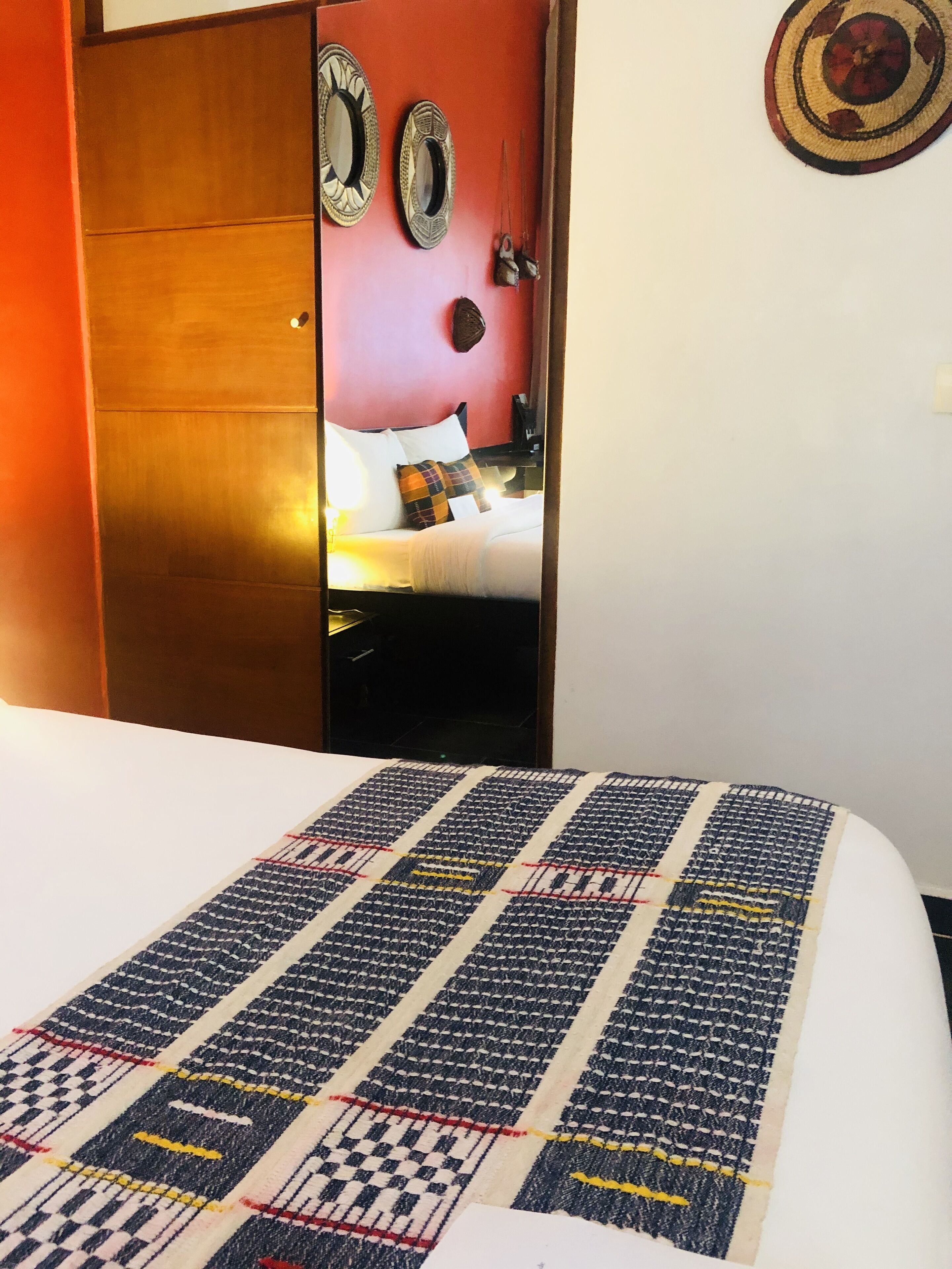 Una habitación de hotel con una cama, un armario de madera y un espejo en la pared.