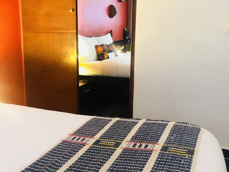 Una habitación de hotel con una cama, un armario de madera y un espejo en la pared.