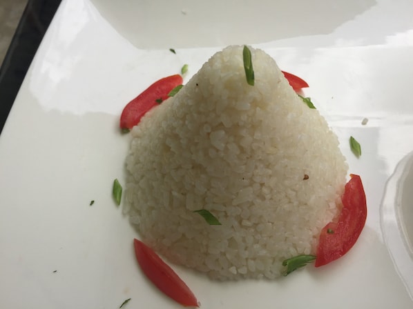 Un plato de arroz blanco con rodajas de chile rojo y hierbas verdes.