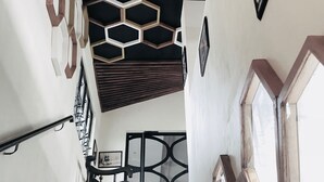 A staircase with a geometric ceiling design, a handrail, and a framed picture on the wall. - Détente Hôtel (Abidjan)