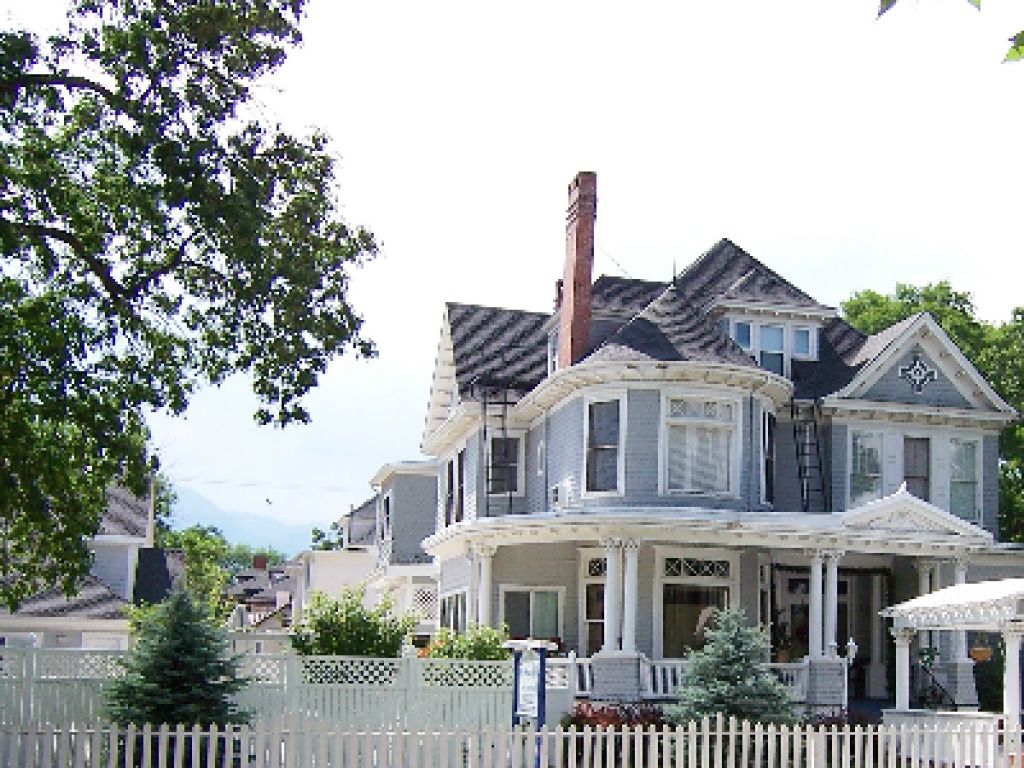 A Victorian-style house with a prominent chimney, a porch with columns, and a picket fence.