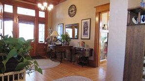 Una habitación amplia con pisos de madera, un candelabro, un escritorio con lámpara y un espejo grande.