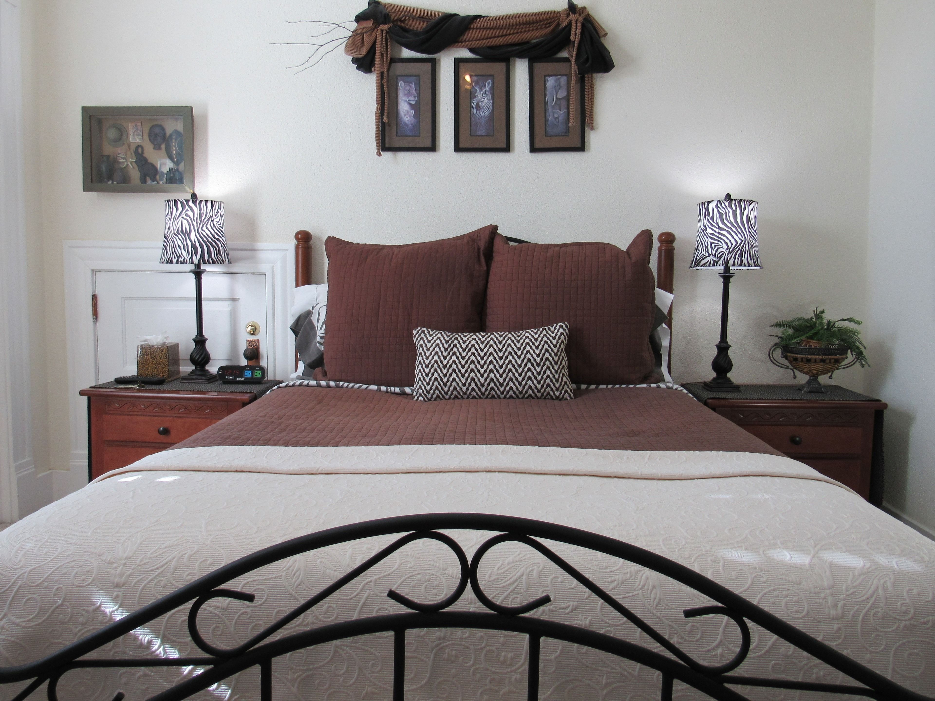 A neatly made bed with a headboard, two bedside tables with lamps, a small decorative item on the nightstand, and a framed picture on the wall.