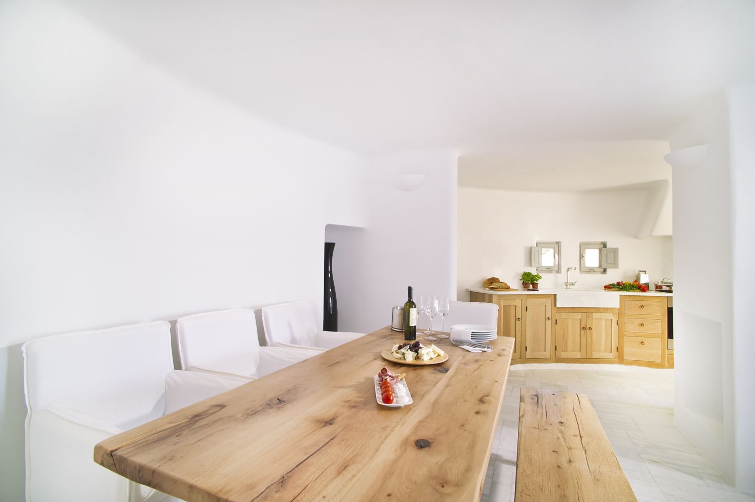 A modern kitchen with wooden cabinets, a white countertop, and a dining area with a wooden table.