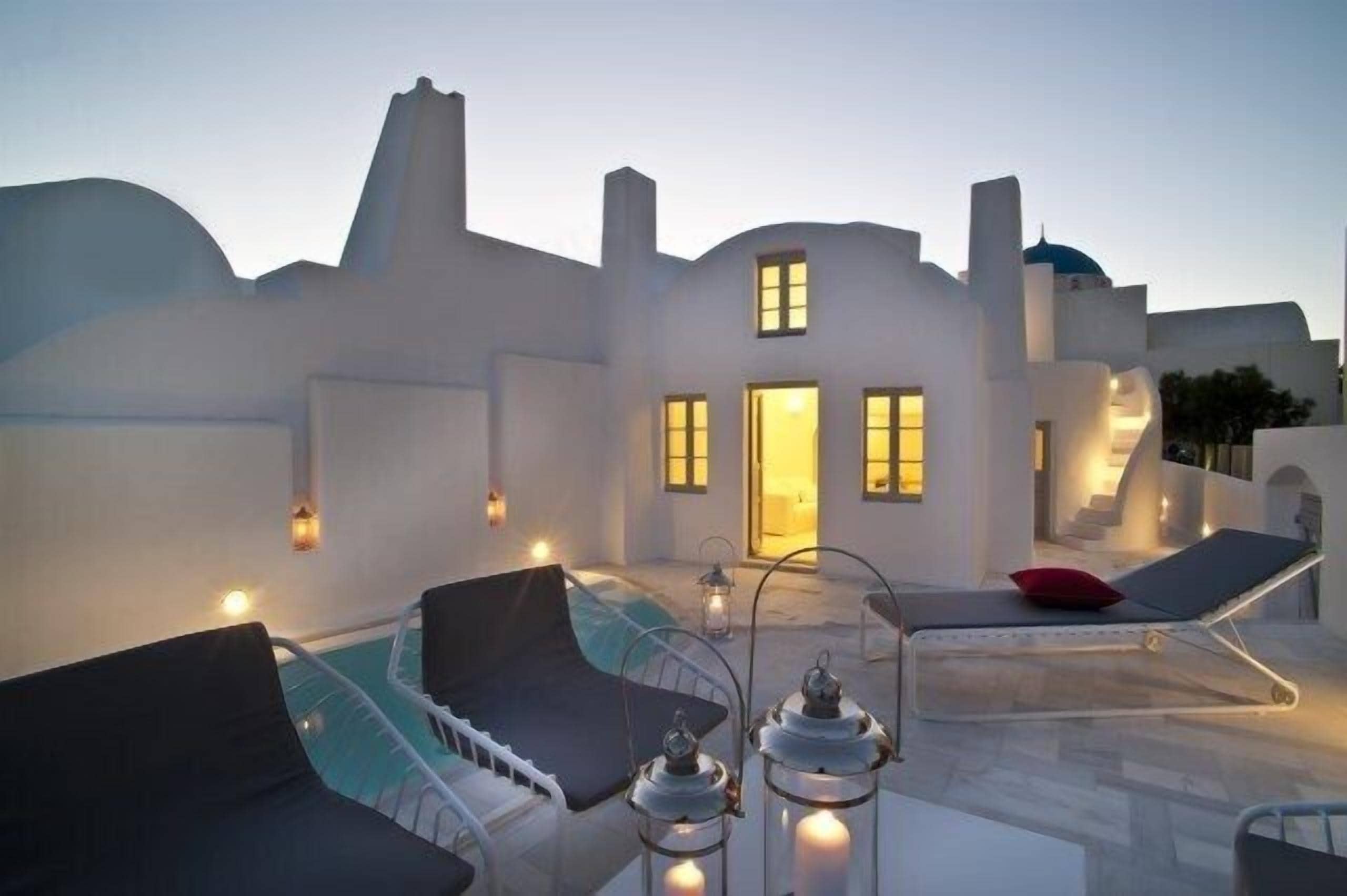 A modern building with a pool area, including lounge chairs and lanterns.