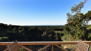 Eine Holzterrasse mit Tisch und Stühlen mit Blick auf ein bewaldetes Tal.