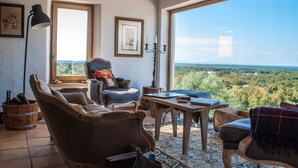 Ein gemütliches Zimmer mit großem Fenster, Holzmöbeln und Blick ins Grüne.