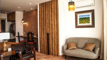Un salón con sofá, pared de paneles de madera, mesa de comedor con sillas y una lámpara colgante.