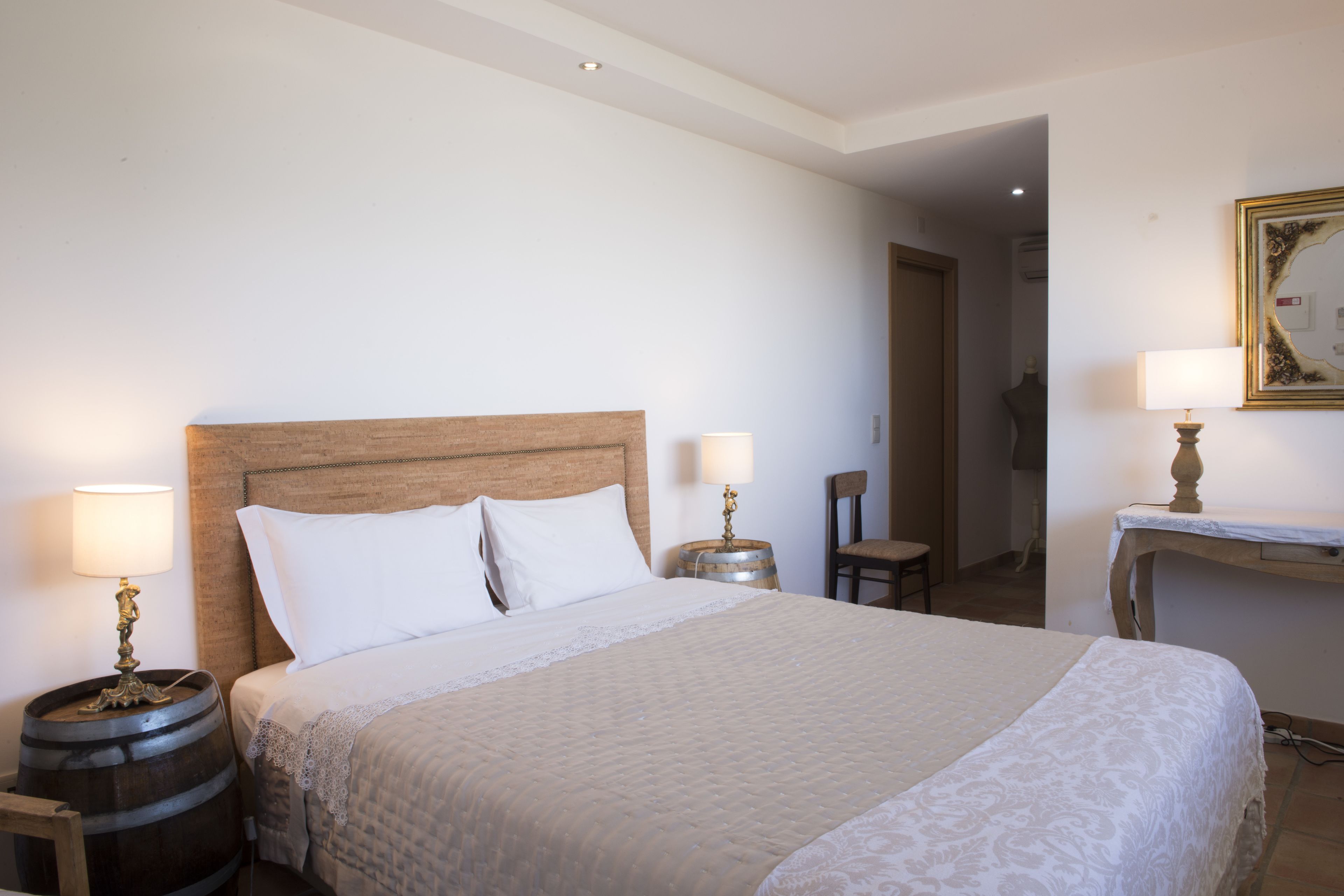 A hotel room with a large bed, two bedside tables with lamps, a wooden headboard, and a small table with a chair.