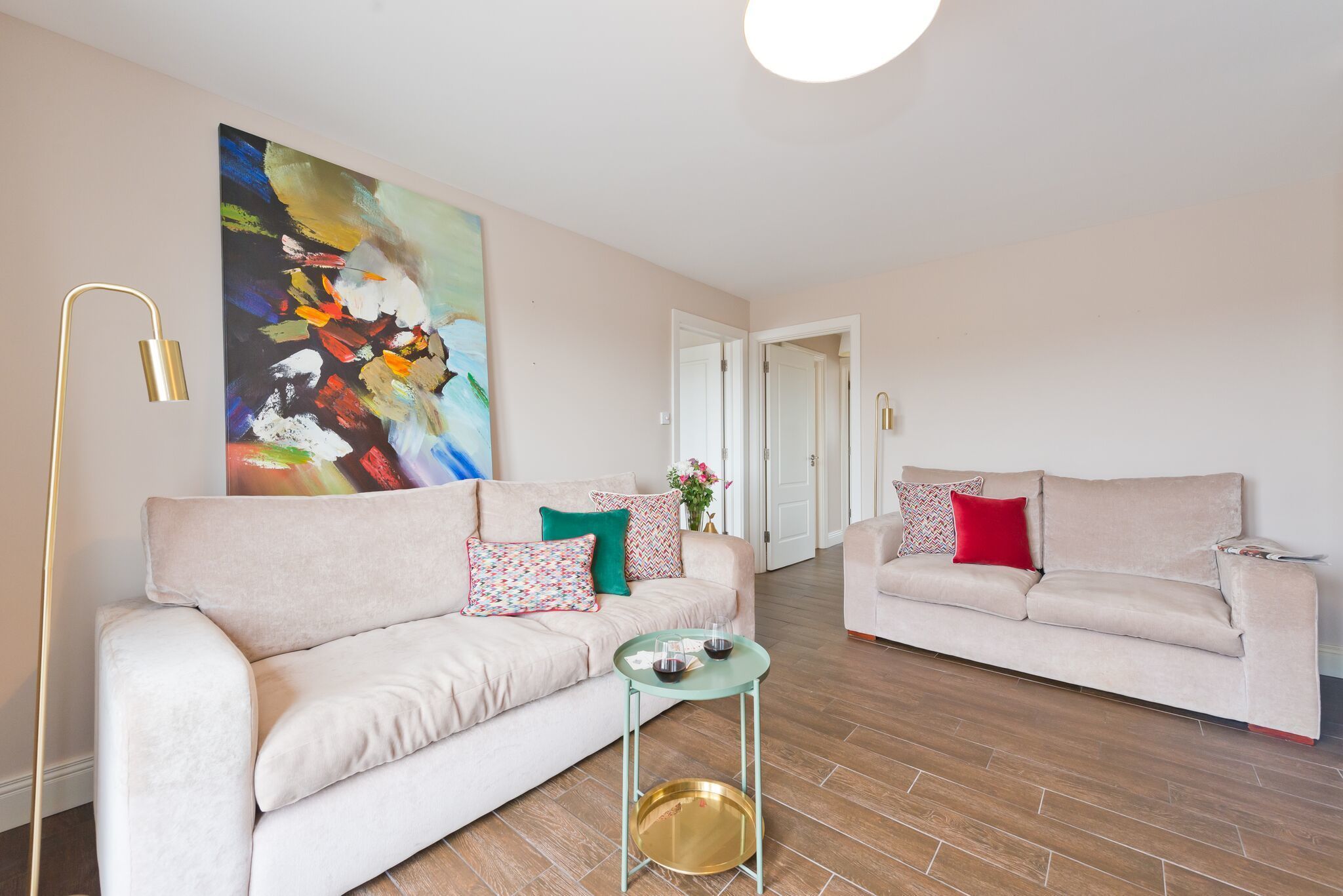 A living room with two sofas, a small table, and a large abstract painting on the wall.