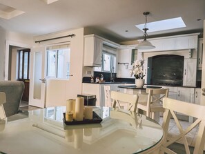 A modern kitchen with white cabinetry, a dining area with a glass table, and a large window providing natural light. - Broc House Suites (Dublin)
