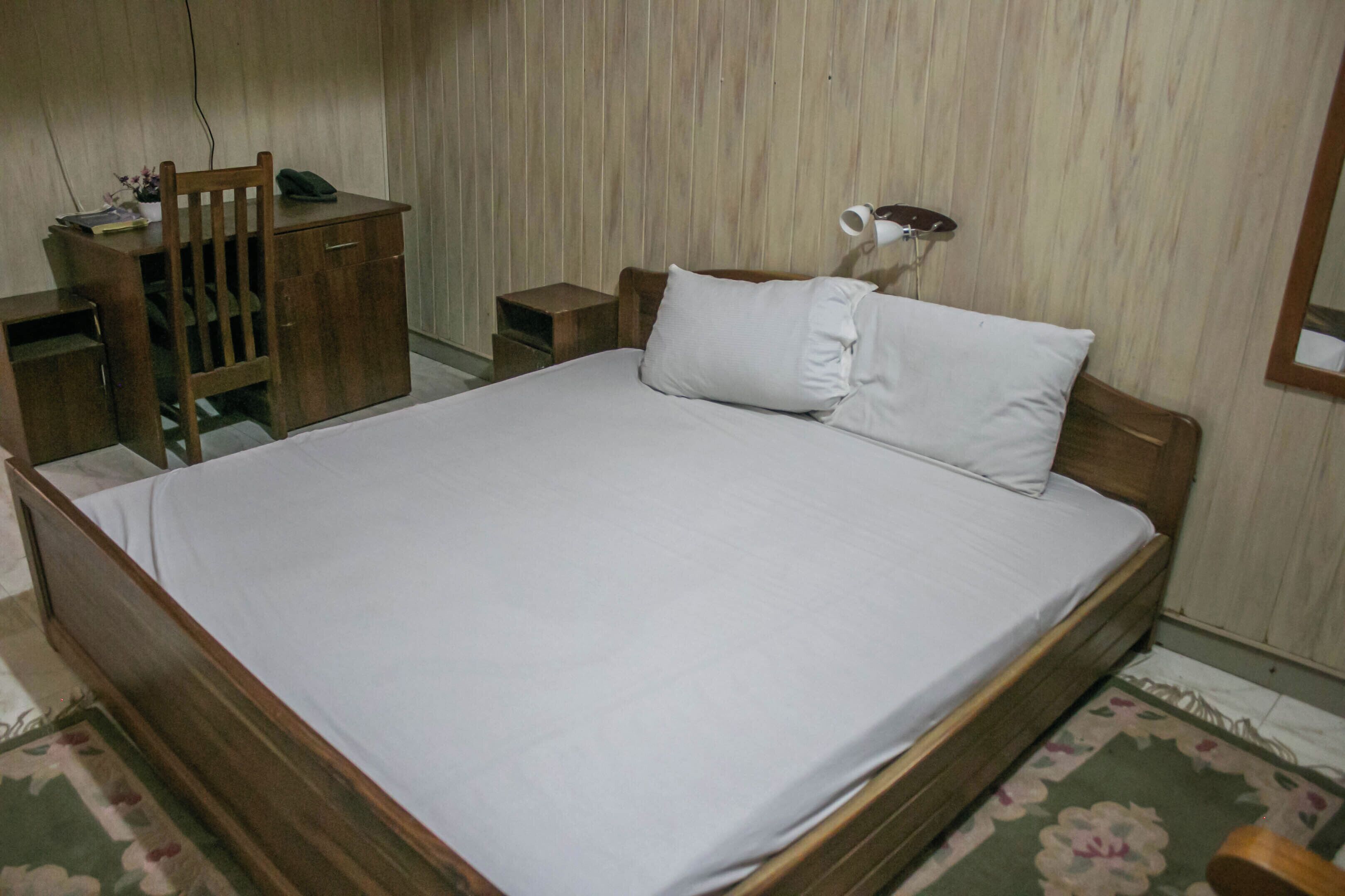 A bedroom with a wooden bed, a desk, and a chair.
