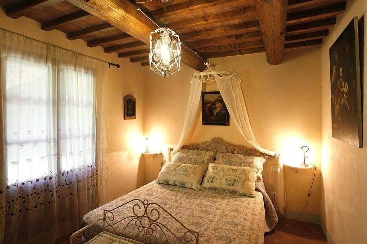 A bedroom with a canopy bed, two bedside lamps, and a wooden ceiling.