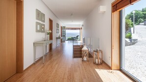 A modern interior with a wooden floor, a dining area with a view, and a large window. - Quinta do Fontelo (Vouzela)